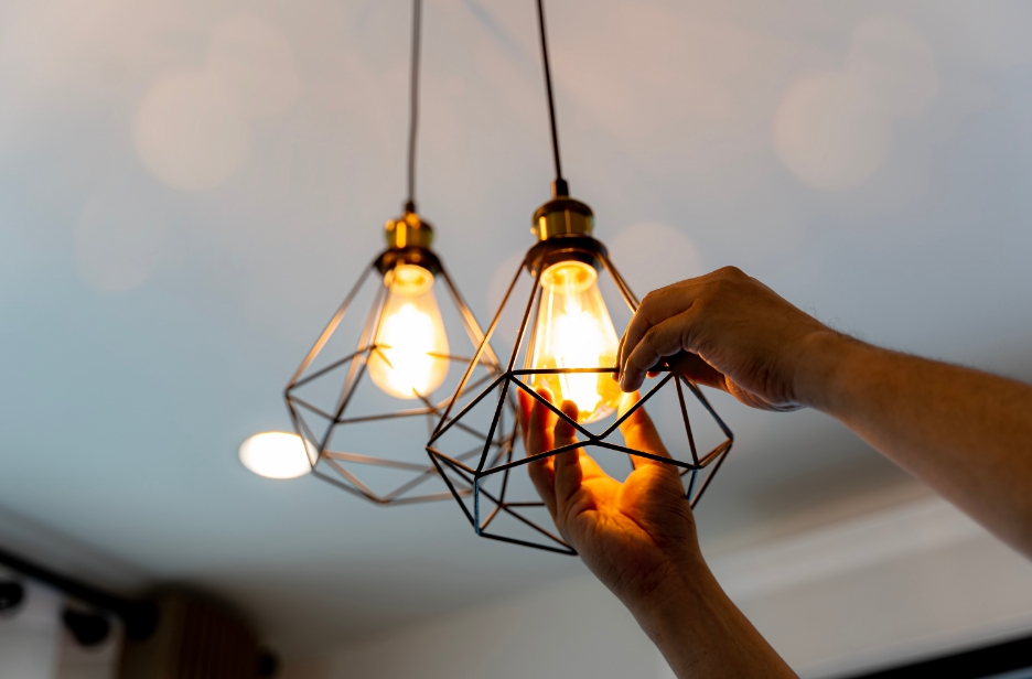 lightbulb being installed in a hanging light fixture that has a geometrical wiring pattern